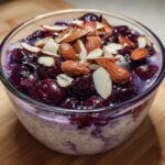 Close-up of Cherry Almond Overnight Oats topped with whole and sliced almonds and dark cherries.