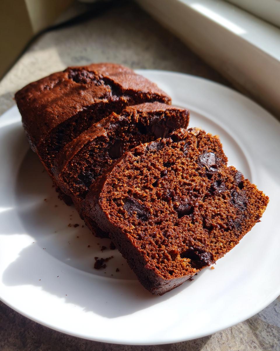 Close-up of thick slices of moist Chocolate Banana Bread studded with chocolate chips on a white plate.