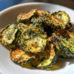 Close-up of crispy, seasoned cucumber chips piled in a white bowl, resembling Cool Ranch Cucumber Chips.