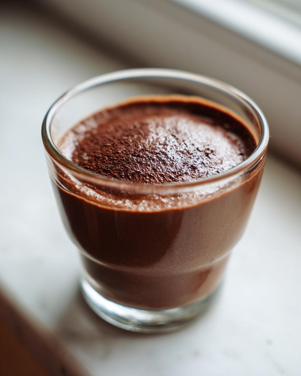 Close-up of rich, dark brown Cottage Cheese Chocolate Mousse topped with cocoa powder in a small glass.