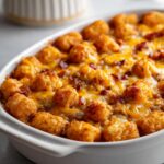 Close-up of a baked Cracked Out Chicken Tater Tot Casserole topped with crispy tater tots and melted cheddar cheese.