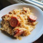 Close-up of a white bowl filled with Creamy Kielbasa And Sauerkraut, topped with paprika.