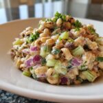 Close-up of a creamy Southern Pea Salad featuring black-eyed peas, chopped celery, and red onion, topped with parsley.