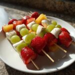 Close-up of fresh fruit and marshmallow Dessert Kabobs featuring strawberries, green grapes, pineapple, and marshmallows.