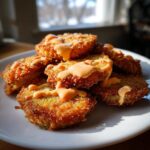 A stack of crispy Fried Green Tomatoes With Comeback Sauce drizzled generously over the top.