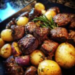 Close-up of juicy Garlic Butter Steak Bites And Potatoes Whole30, garnished with fresh rosemary.