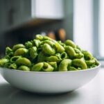 A close-up of a white bowl filled with elbow macaroni coated in bright green Green Goddess Mac And Cheese sauce.