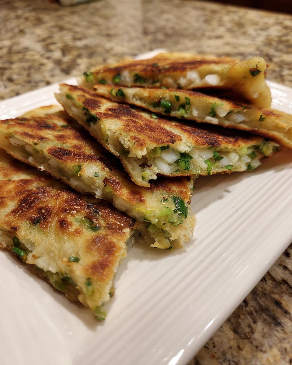 Close-up of flaky, grilled Garlic Scallion Pancakes cut into wedges, showing green scallions inside.