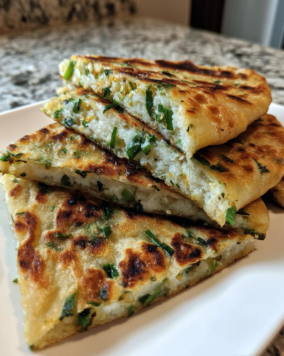 Close-up of stacked, golden-brown slices of Grilled Garlic Scallion Pancakes showing the fluffy interior and green scallions.