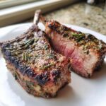 Two perfectly cooked Grilled Lamb Chops With Rosemary, showing a medium-rare pink center and herb crust.