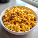 A white bowl filled with creamy, cheesy macaroni mixed with chunks of Impossible Steak Bites, showcasing the High Protein Mac Cheese.