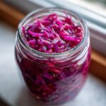 Close-up of vibrant, thinly sliced pickled red onion magic filling a glass jar.