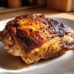 Close-up of a perfectly cooked, juicy slow cooker chicken thigh with crispy, browned skin.