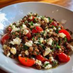 Close-up of Mediterranean Ground Beef Stir Fry topped with crumbled feta cheese and halved cherry tomatoes.