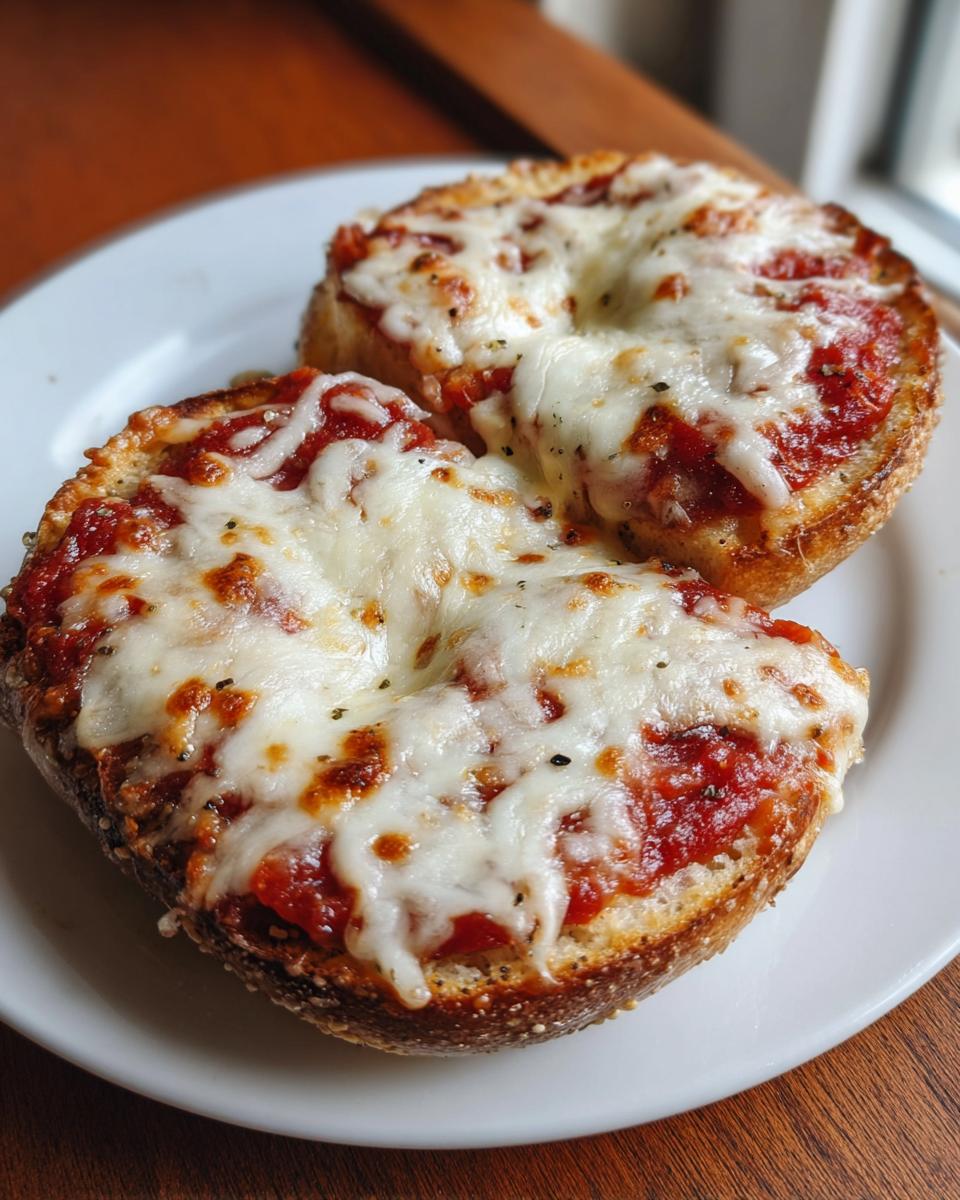 Close-up of two freshly baked Freezer Bagel Pizzas topped with melted mozzarella cheese and tomato sauce.