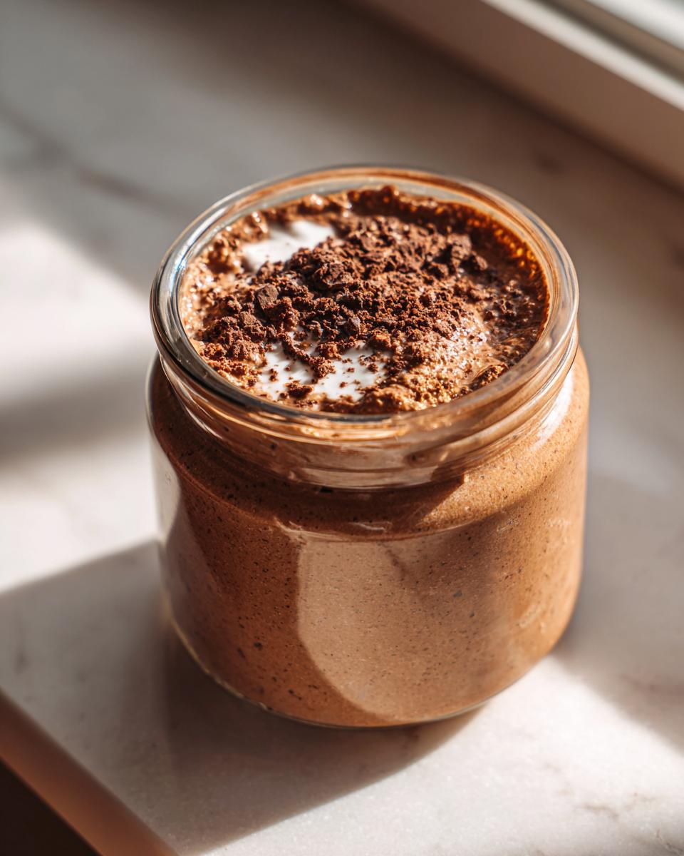 A glass jar filled with creamy Mocha Overnight Oats topped with chocolate shavings.