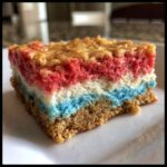 Close-up of a layered Patriotic Graham Cracker Frozen Treats bar with red, white, and blue filling on a graham crust.