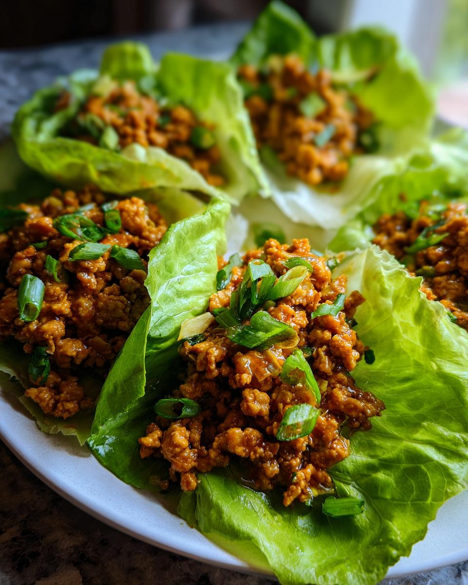 Close-up of several Asian Lettuce Wraps filled with savory ground meat mixture and topped with sliced green onions.