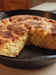 Close-up of a freshly baked Pumpkin Snickerdoodle Skillet Cookie with a cinnamon-sugar topping in a cast iron pan.