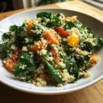 A close-up of a vibrant Quinoa Spinach Power Salad featuring quinoa, fresh spinach leaves, and chunks of orange sweet potato or squash.