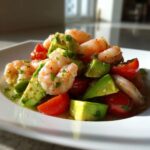 Close-up of a bright Refreshing Shrimp And Avocado Salad with chunks of avocado and halved cherry tomatoes.