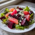 Close-up of a Roasted Beet Grapefruit Blue Cheese Salad featuring dark beets, pink grapefruit segments, and crumbled blue cheese on lettuce.