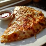 A crispy, golden-brown slice of Smashburger Quesadillas oozing cheese, served with a side of ketchup.