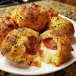 Close-up of Sourdough Pizza Bombs, one broken open showing melted cheese and pepperoni filling.