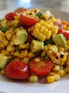Close-up of a Summer Corn Salad With Avocado, featuring grilled corn kernels, chunks of avocado, and halved cherry tomatoes.