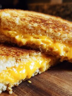 Close-up of a Sweet Waffle Grilled Cheese For Breakfast cut in half, showing gooey melted cheddar cheese.