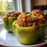 Three bright green bell peppers filled with a savory rice and turkey mixture, served as Turkey Stuffed Peppers.