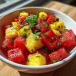 Close-up of a vibrant Watermelon Pineapple Salad Recipe, featuring cubed fruit topped with fresh mint.