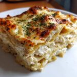Close-up of a layered slice of White Cheese Chicken Lasagna topped with melted, browned cheese and parsley.