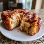 A close-up of a section of Apple Fritter Pull Apart Bread, showing soft dough, caramelized apples, and a light glaze.