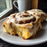 Close-up of a fluffy Breakfast Sausage Roll With Sausage Gravy Frosting, drizzled heavily with white glaze.
