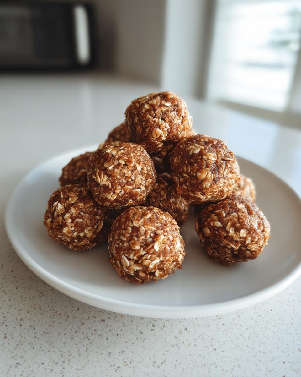 A close-up stack of No Bake Banana Cinnamon Energy Bites coated in oats, served on a white plate.