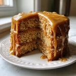 A tall slice cut from the Ultimate Butterscotch Cake, generously covered in dripping butterscotch glaze.